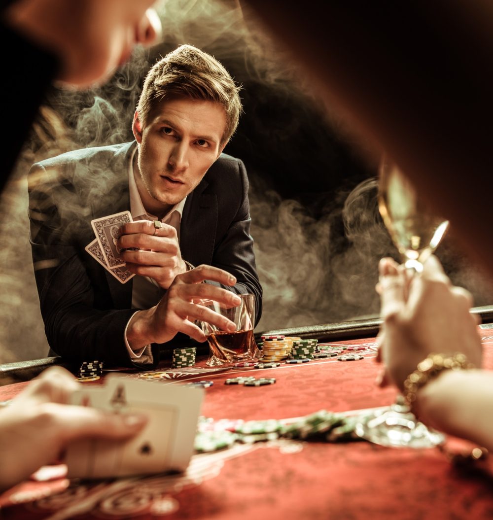concentrated man with drink and poker cards looking at woman in casino concentrated man with drink and poker cards looking at woman in casino